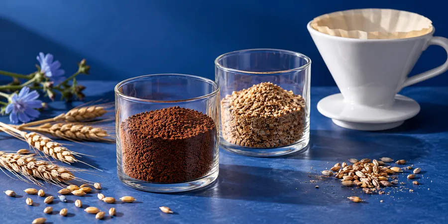 Löslicher und gemahlener Getreidekaffee in zwei Gläsern neben einem Filter